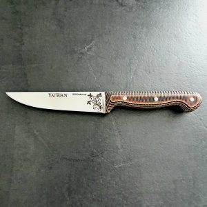 Couteau d'office avec lame en acier inoxydable et manche en Werzalit cuivré, posé sur un plan de travail en bois.